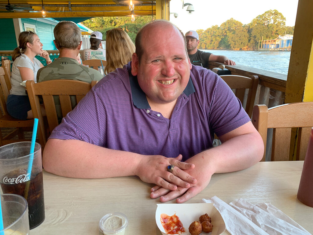 Clayton smiles while sitting down enjoying dinner by the water