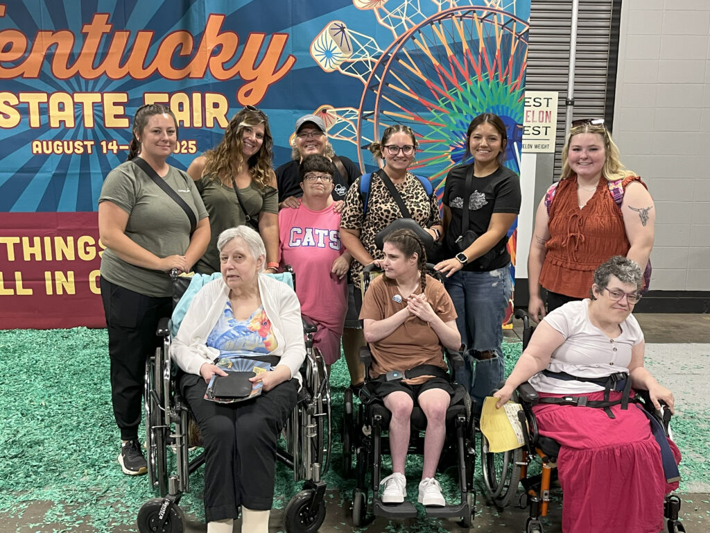 Individuals and staff at Cedar Lake Park Place pose in front of Kentucky State Fair Sign