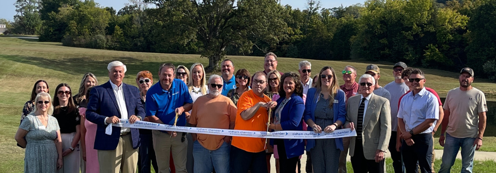 Cedar Lake Lodge Path Ribbon Cutting Individuals Behind Ribbon Ready to Cut
